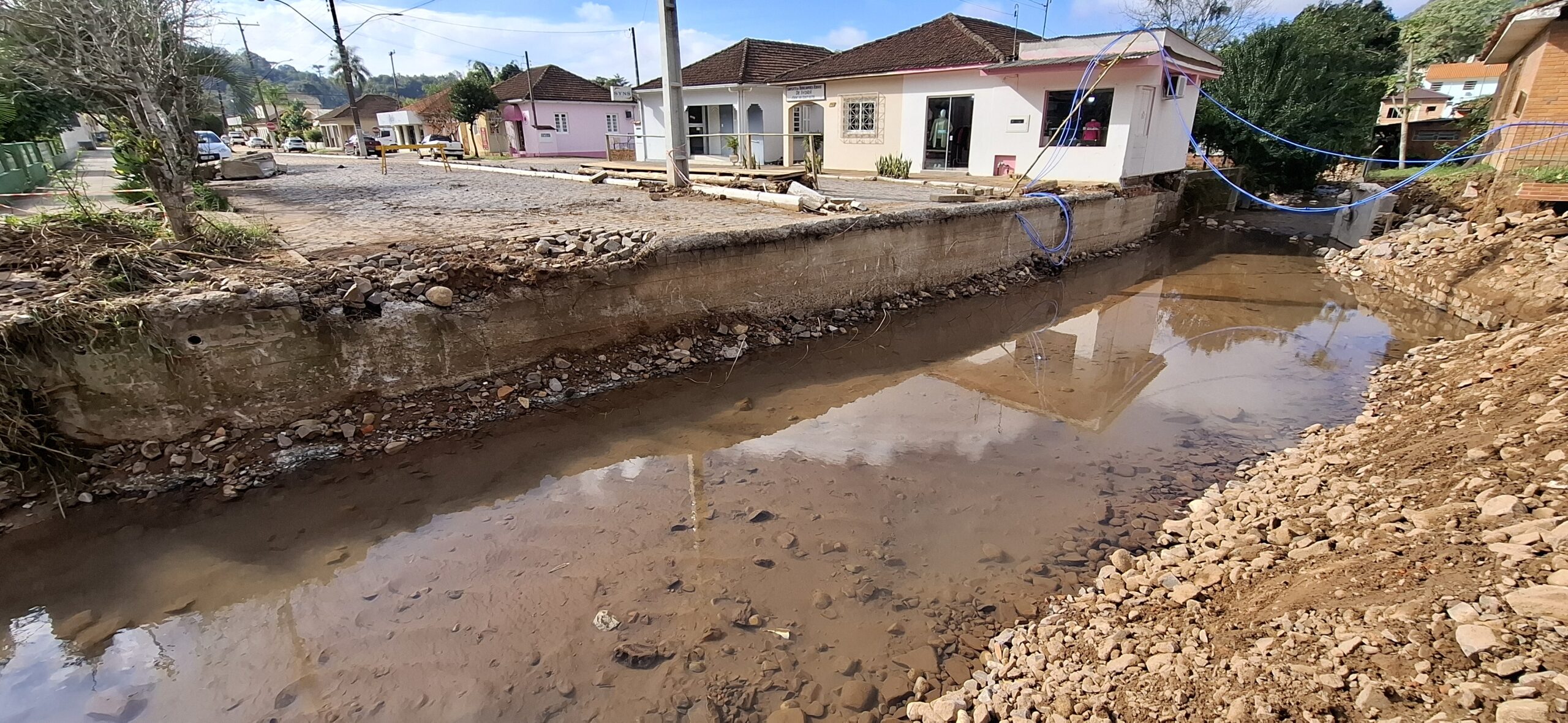 Canal urbano junto a ruas e edificações com sinais de erosão