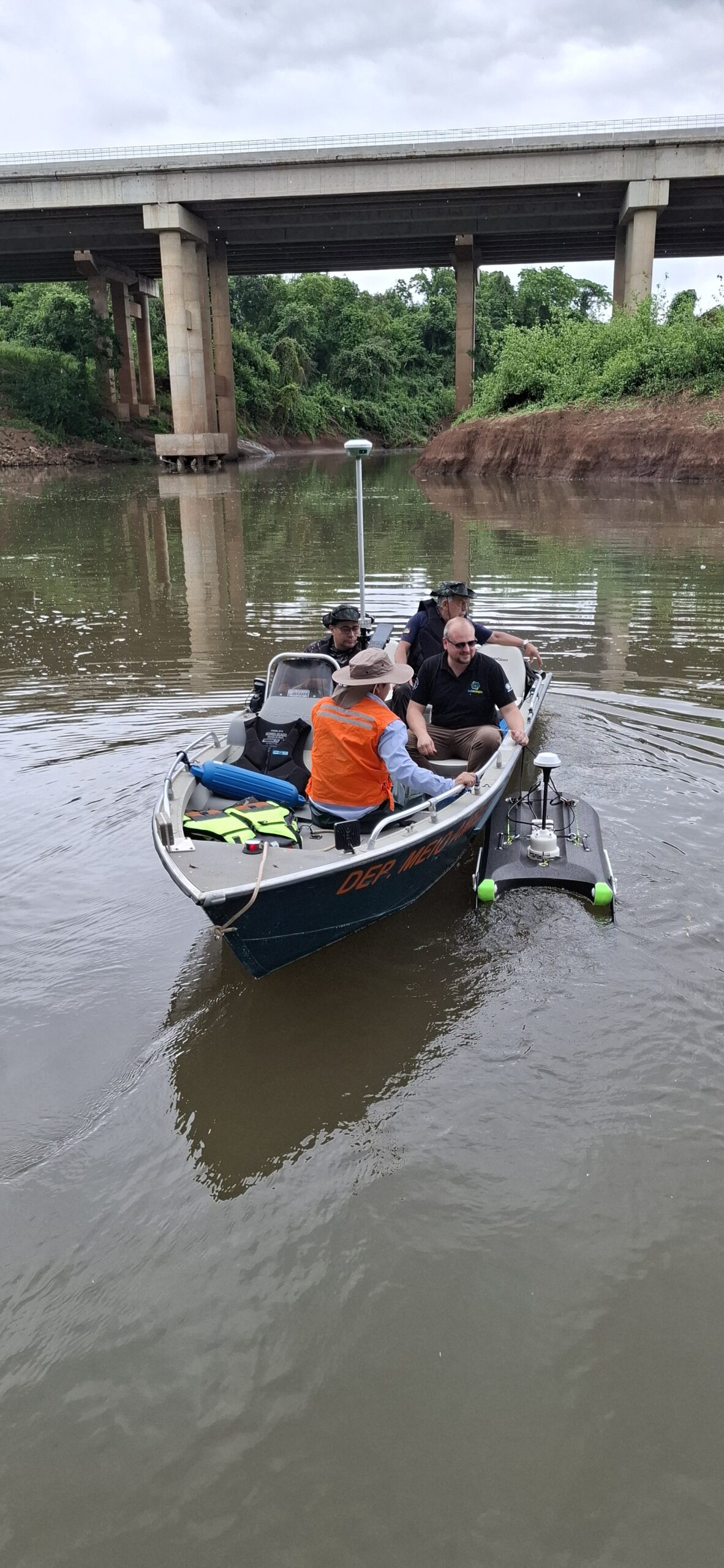 Equipe realizando levantamento hidrométrico em embarcação sob uma ponte