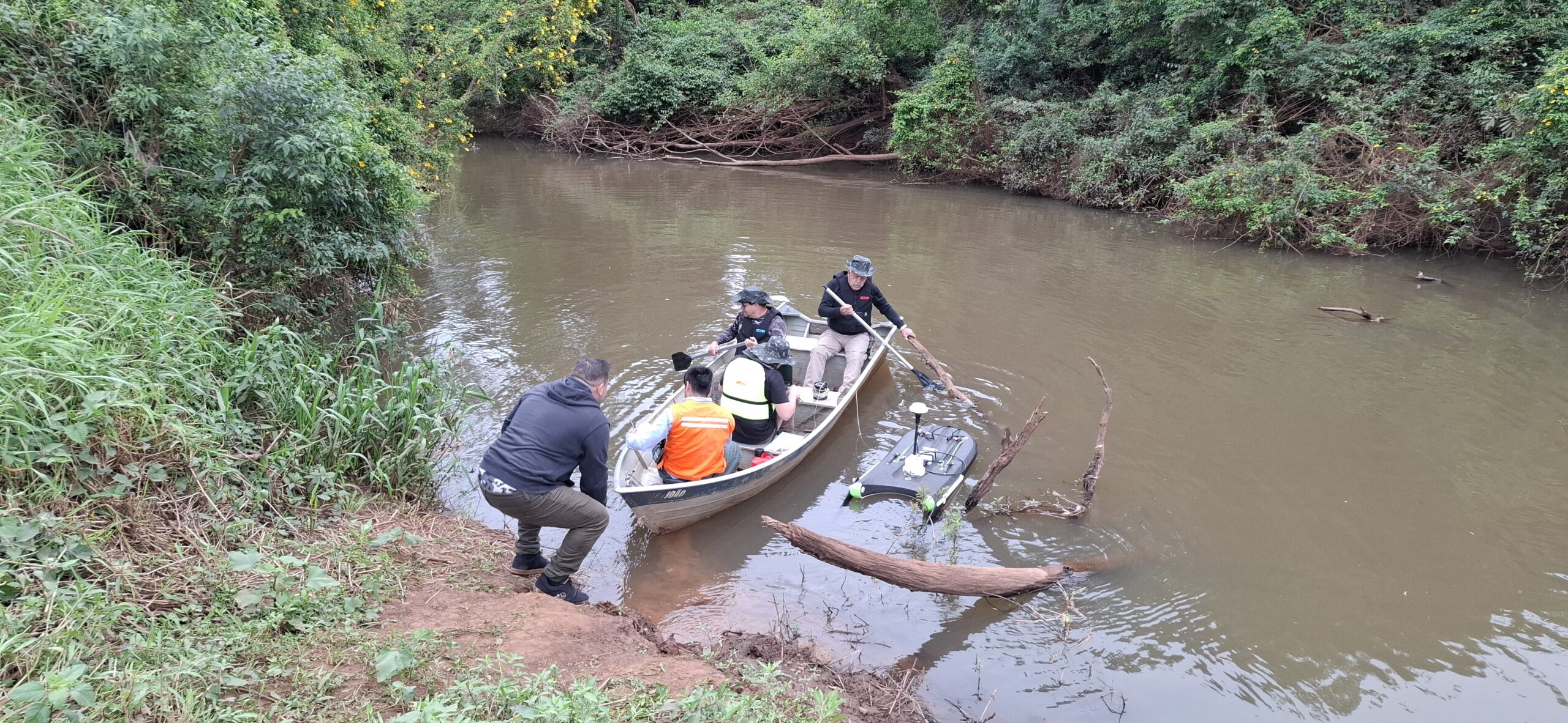 Equipe preparando embarcação e instrumentos para medição hidrométrica em um rio