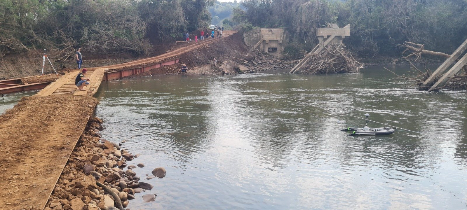 Equipe avaliando uma ponte destruída sobre um rio